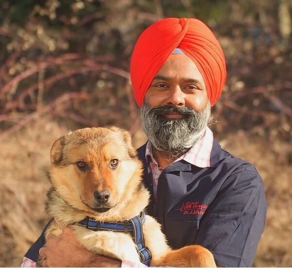 Dr. Jatinder Mundi, owner and veterinarian at Gladys Pet Hospital, holding a dog
